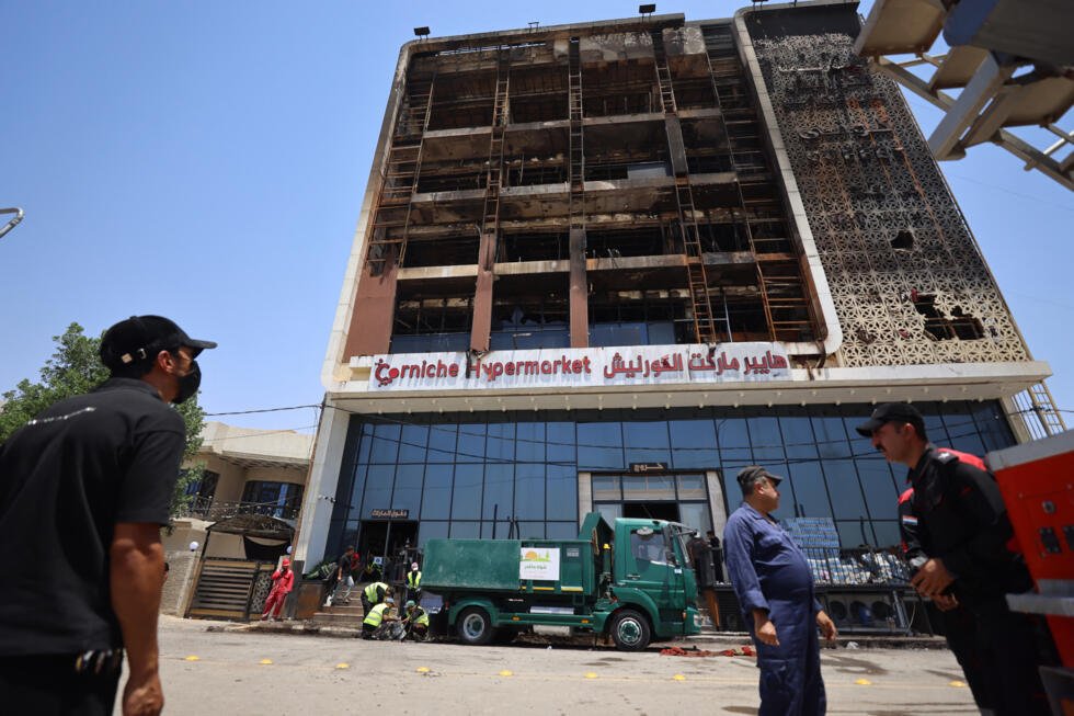 A cleaning operation starts outside the charred building on July 17, 2025, after a fire tore through the newly opened Hyper Mall overnight in the eastern Iraqi city of Kut.